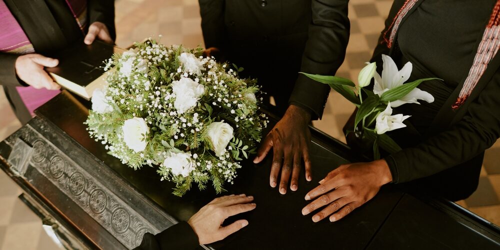 High,Angle,Shot,Of,Unrecognizable,Hands,On,Black,Wooden,Coffin