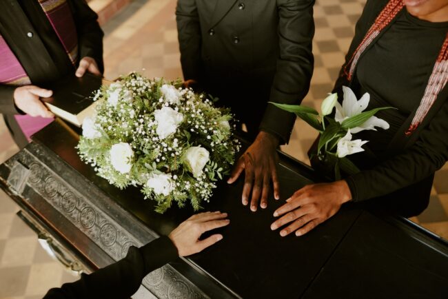 High,Angle,Shot,Of,Unrecognizable,Hands,On,Black,Wooden,Coffin